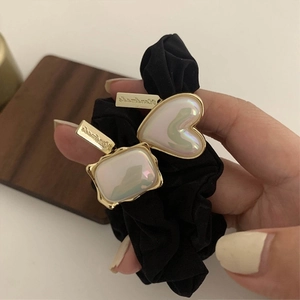 Detail of black fabric scrunchie with pearlescent heart charms and handmade metal tag
