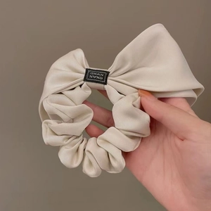 Elegant beige satin scrunchie with large bow and vintage square brand label detail