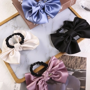 Detail showing various colors of satin bow scrunchies with metallic charms