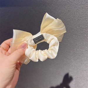 Detail of cream organza bow scrunchie with hand made label and satin texture