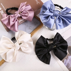 Detailed set of four large satin bow scrunchies in pastel colors with gold metal tags