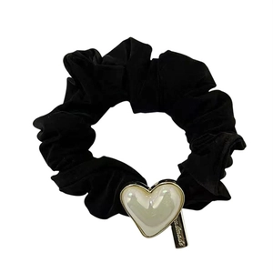 Detail of black velvet scrunchie with pearlescent heart charm and handmade metal tag