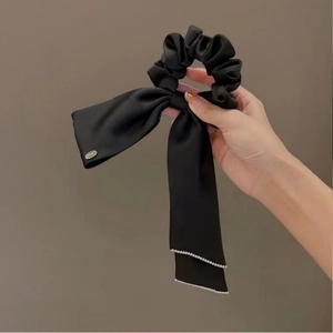 Close-up of black satin scrunchie with long ribbons and delicate bead edge detailing