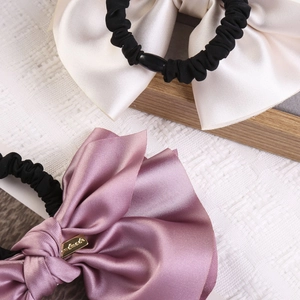 Detailed macro view of white and pink satin bow scrunchies with elegant handmade metal tag
