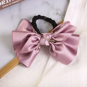 Detail of elegant satin bow scrunchie in dusty pink with a luxury gold metallic buckle