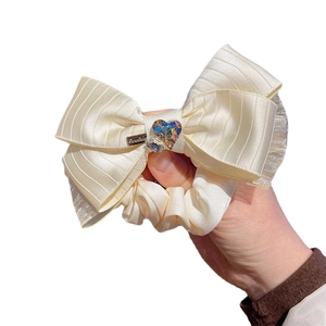 Elegant cream satin bow scrunchie with sparkling crystal heart center and fine textures