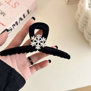 Macro detail of black flocked hair claw clip featuring a silver rhinestone snowflake charm