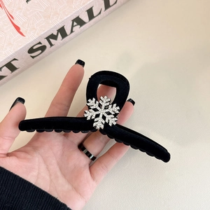 Close-up of a large black velvet hair claw clip with a sparkling silver snowflake