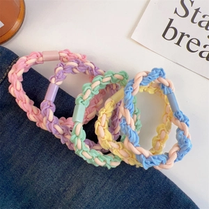 Close-up of four colorful woven elastic hair ties with pastel buckles on denim background