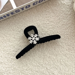 Macro detail of black velvet shark hair clip with sparkling rhinestone snowflake ornament