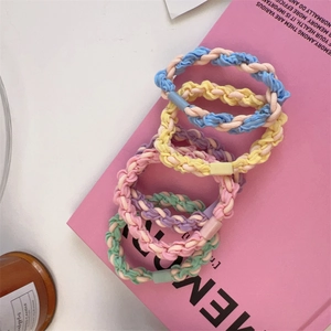 Detail of five macaron-colored braided hair ties arranged on a pink magazine