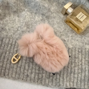 Pink plush square hair claw clip with golden crystal earring on grey knit fabric