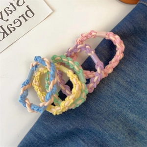 Set of four colorful woven elastic hair ties in pastel shades on denim fabric