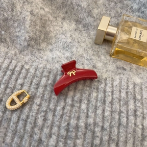 Pince à cheveux rouge élégante avec nœud doré sur fond en maille grise