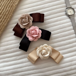 Detailed view of camellia bow hair clips in coffee, black, and champagne satin