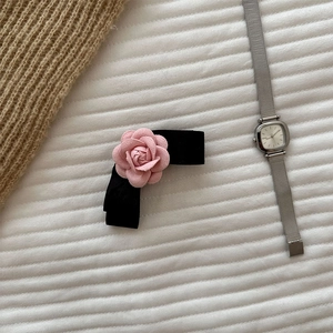 Close-up of elegant camellia bow hair clip with pink fabric flower on white fabric