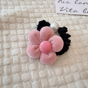 Detalle de coletero con flor de peluche rosa y perla blanca sobre tela de gofre suave
