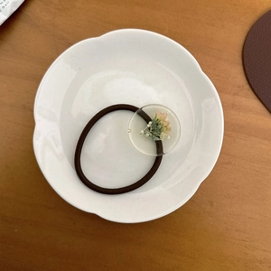 Détail d'un élastique à cheveux marron foncé avec ornement en résine et fleurs séchées