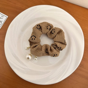Gros plan sur chouchou en velours côtelé marron avec smileys et perles blanches