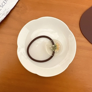 Détail d'un élastique à cheveux marron avec pendentif en résine et fleur séchée rose