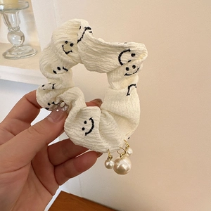 Détail d'un chouchou blanc avec imprimés smiley et breloques en perles blanches