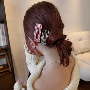 Detail of red and black checkered knit hair clips worn on the hair for a cozy look