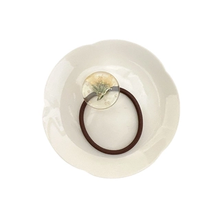 Élastique à cheveux en résine avec fleurs séchées et perles sur assiette blanche