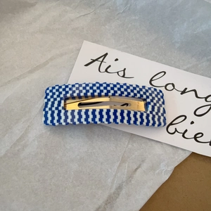 Blue and white checkered acetate hair clip with wavy edges and hollow square design