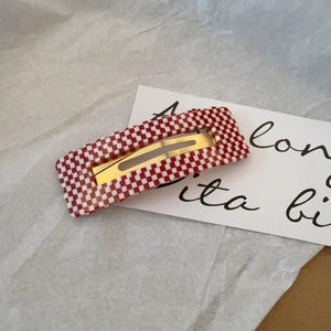 Macro view of rectangular red and white checkerboard hair clip with gold metal buckle
