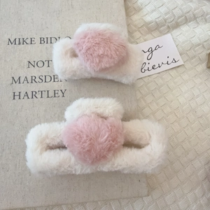Dettaglio di fermagli per capelli in peluche crema con cuori rosa su libro vintage