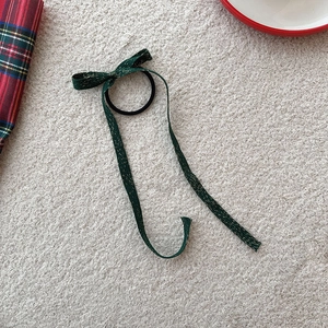 Gros plan d'un chouchou noeud vert foncé avec fils dorés sur une surface texturée