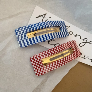 Detail of red and blue checkerboard hair clips with wavy edges on marble background