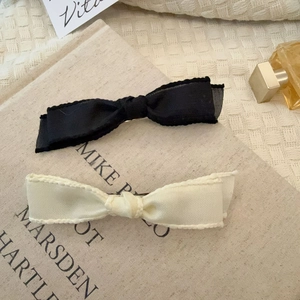 Set of black and beige satin bow hair clips with refined texture on vintage book cover