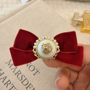 Vue détaillée du nœud en velours rouge vintage avec emblème rose et perles