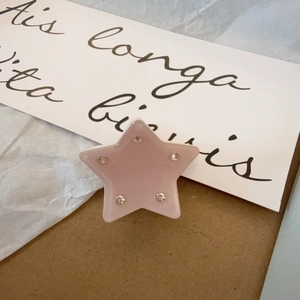 Vista detallada de una linda pinza de estrella rosa con cinco diamantes de imitación