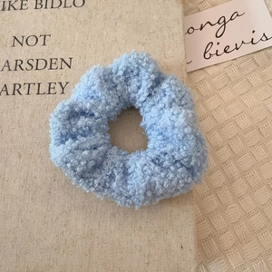 Chouchou en laine d'agneau bleu clair avec texture douce sur fond en lin
