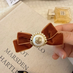 Détail du nœud en velours vintage avec camélia en relief et perles sur la pince