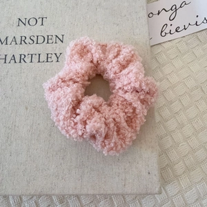 Chouchou en peluche rose avec texture mouton sur un fond esthétique et chaleureux