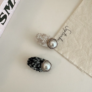 Detail of tweed fabric hair clips with central pearl inlay and vintage metal border