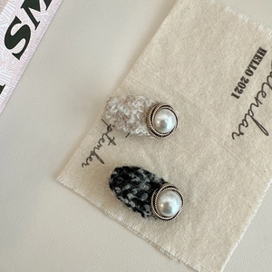 Detailed close-up of tweed hair clips with faux pearls and golden metal trim accents