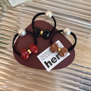 Close-up of three bow and pearl elastic hair ties in black, red, and dark brown colors