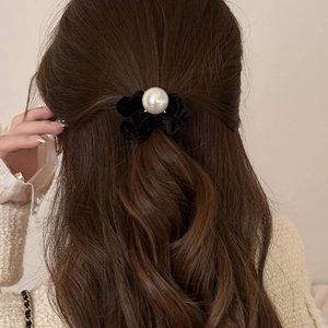 Elegant black velvet scrunchie with large pearl accent on wavy dark hair for women