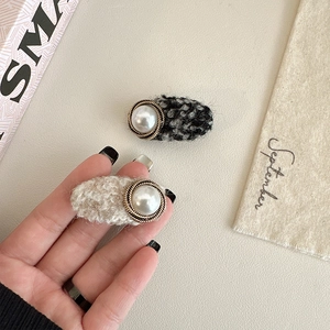 Detail of tweed hair clips with faux pearls and gold woven edges in elegant style