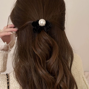 Elegant black velvet hair scrunchie with a large pearl accent on dark wavy hair