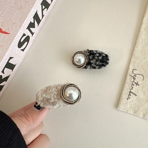 Close-up of French vintage tweed hair clips with large white pearls and metal edging