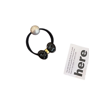 Elegant black bow hair tie with pearl accent and golden charm on elastic band