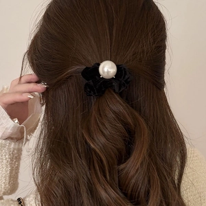 Close-up of black velvet scrunchie with a large pearl detail on a half-up hairstyle