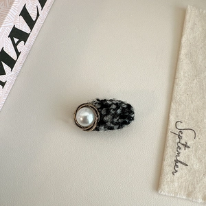 Detail shot of tweed hair clip with large faux pearl and elegant gold metal trim
