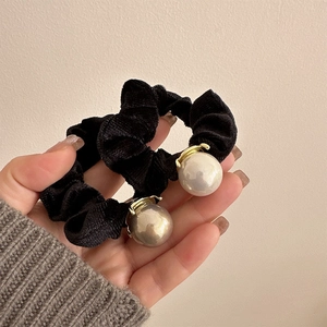 Detail of a velvet scrunchie in black featuring double white and grey pearl accents
