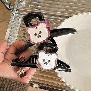 Dettaglio di un grande fermaglio per capelli a forma di orso nero con glitter rosa